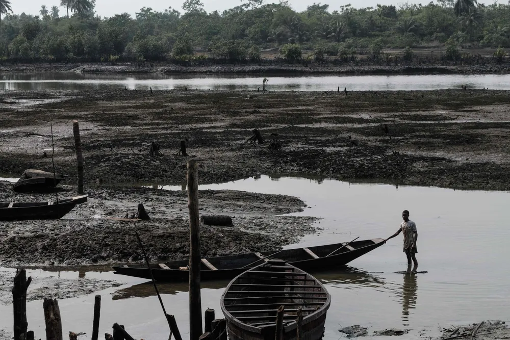 A fisherman pushes his boat on oily mud near Bodo in Nigeria's Niger Delta in February 2019.
