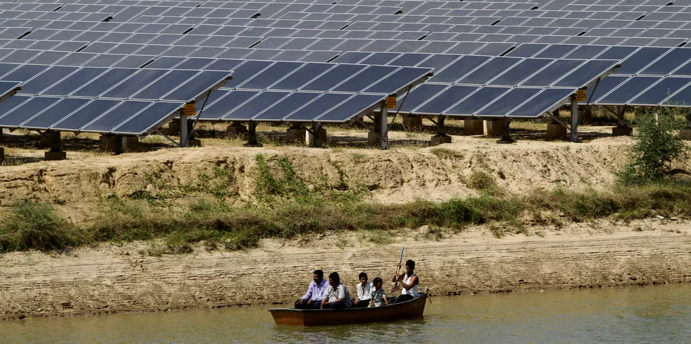 Boat passes by solar farm at Gunthawada in Gujarat state, northern India