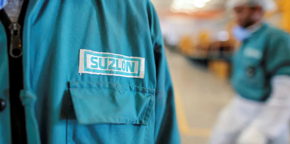 The Suzlon Energy Ltd. logo is displayed on an employee's uniform at the company's rotor blade manufacturing plant in Bhuj, India.