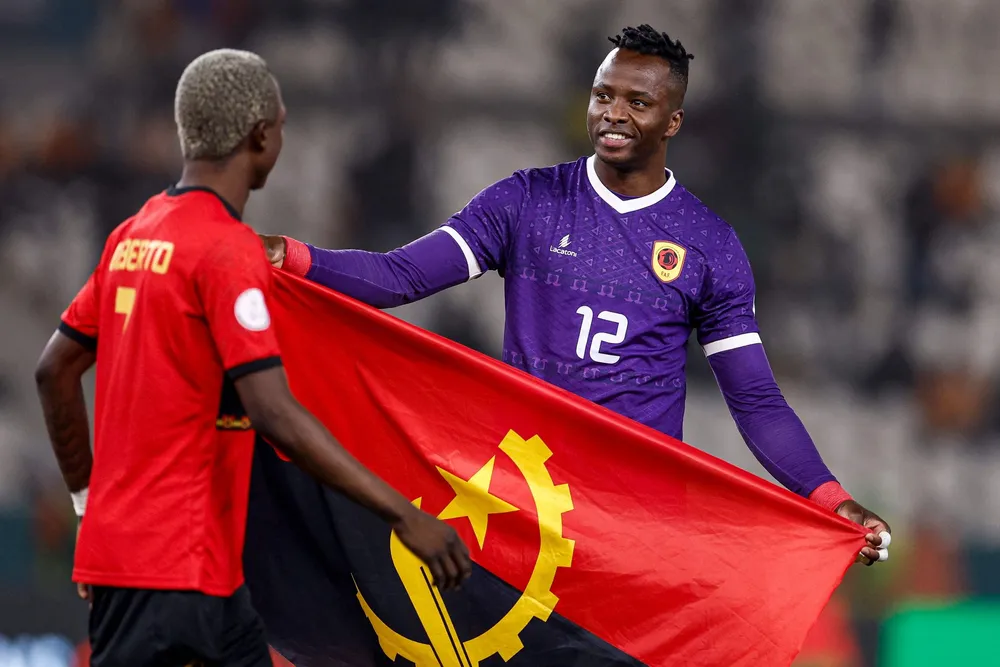 Angolan football players hold the country's flag after winning a match in the Africa Cup of Nations in 2024.