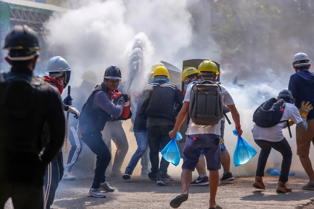 Demonstranter bruker brannslukningsapparater for å beskytte seg mot tåregass i Yangon i mars i år. Protestene var svar på kuppet i februar.