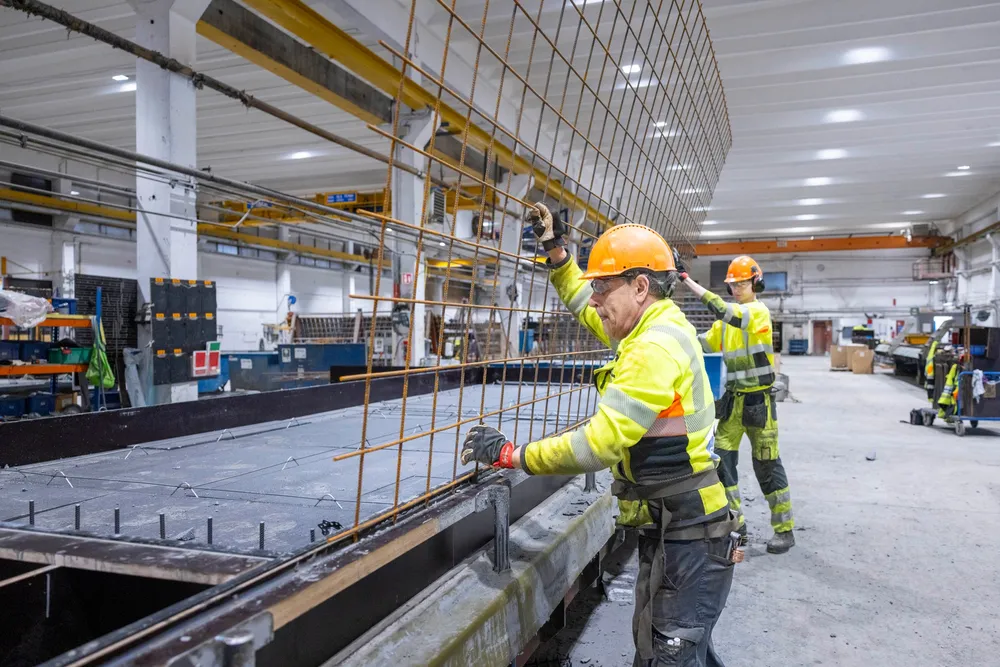 Operatør Rafael Gonsales og lærling i betongfag Sindre Gårdhammer i Spenncon legger armeringsnett på den isolerte betongveggen før siste støp.