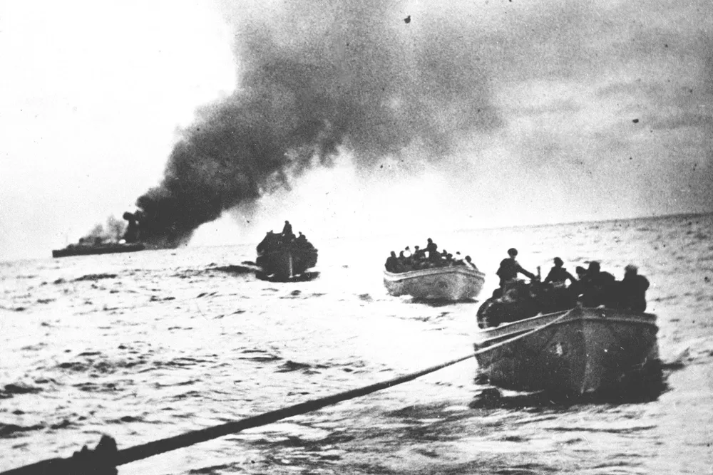 Helt siden tredveårskrigen på 1600-tallet har Norge vært storprofitør hver gang det har vært krig ute i verden, skriver artikkelforfatteren. Her under andre verdenskrig, «Columbus» ble torpedert og står i brann, og mannskapet er i livbåter på vei mot «Tuscaloosa» som tar dem ombord.