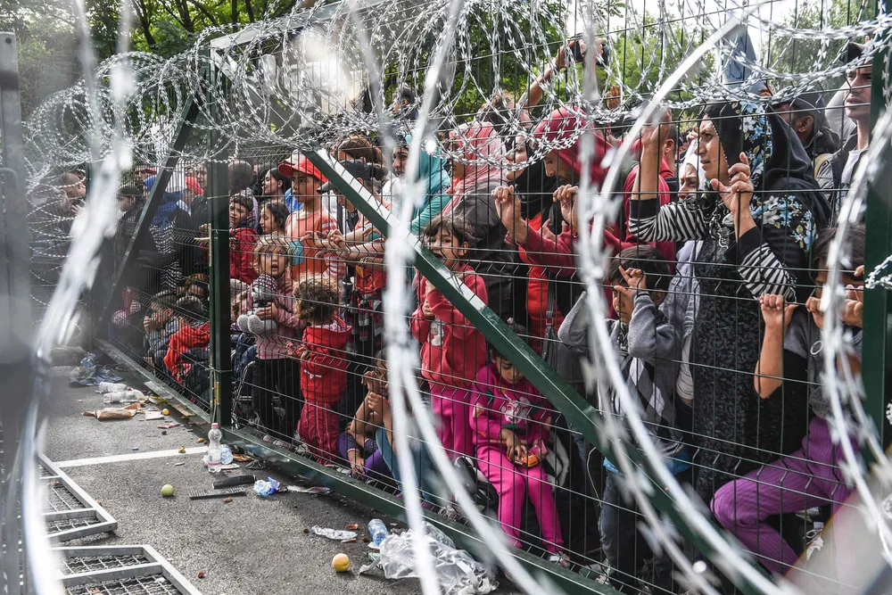 På grensen. Migranter ved grensegjerdet mellom Serbia og Ungarn i 2015. EU vil styrke yttergrensene for å bevare grenseløs trafikk innad i Schengen-sonen.