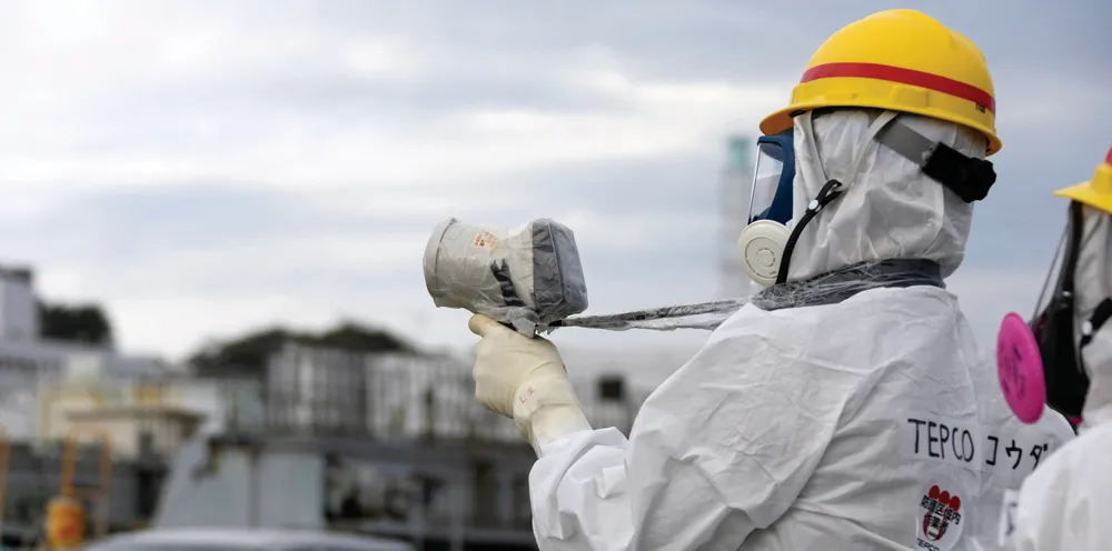 A Tokyo Electric Power Co. employee wearing a protective suit and a mask uses uses a survey meter at the Fukushima Dai-ichi nuclear power plant in 2013.