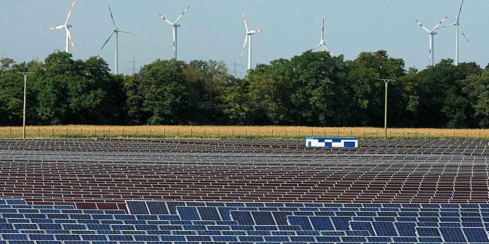 Wind turbines spin behind a field of solar cell panels near Bitterfeld, Germany