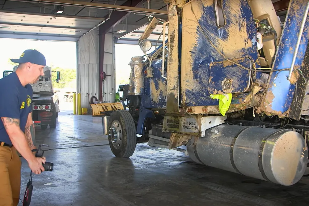 The crashed ammonia tanker truck being photographed, in a screenshot from a video released by the National Transportation Safety Board.