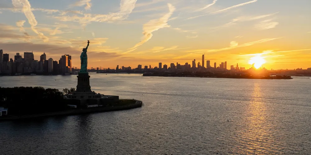 The Statue of Liberty and New York City at sunrise.