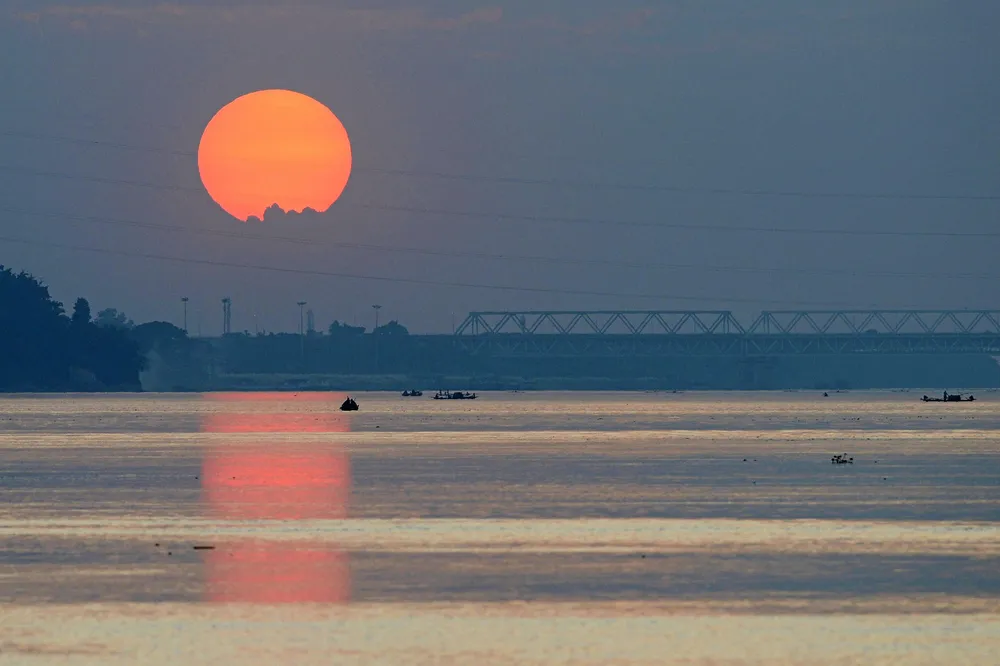 Assam: Indian fishermen work on their boats along the Brahmaputra River as the sun sets in Guwahati