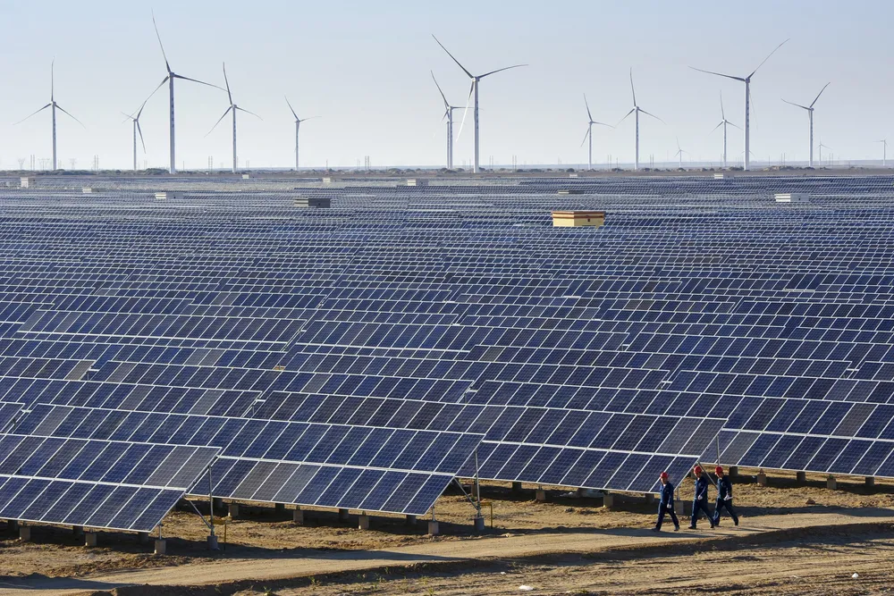 Kinas stadig billigere og bedre produksjon av batterier, elbiler, solcelle, vindmøller, er en av grunnene til at de vinner og vi taper konkurransekraft. På bildet ses vindmøller og solceller i Xinjiang-provinsen i Kina.