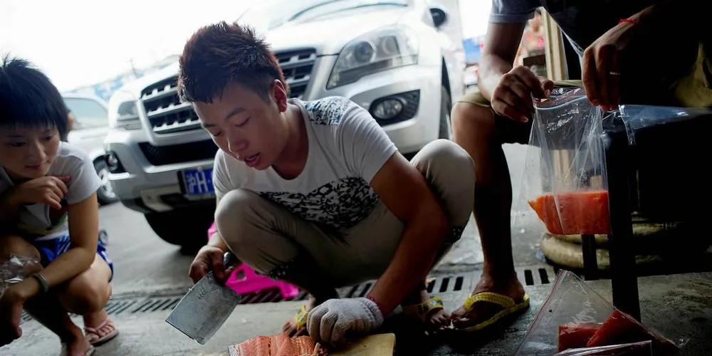 SMUGLER FISK: Ms Tu, MR Ruan og MR Li på fiskemarkedet i Shanghai. Alle sier de kommer fra Norge, men på mange av kassene står det fra Skottland og Færøyene. Foto: Mikaela Berg