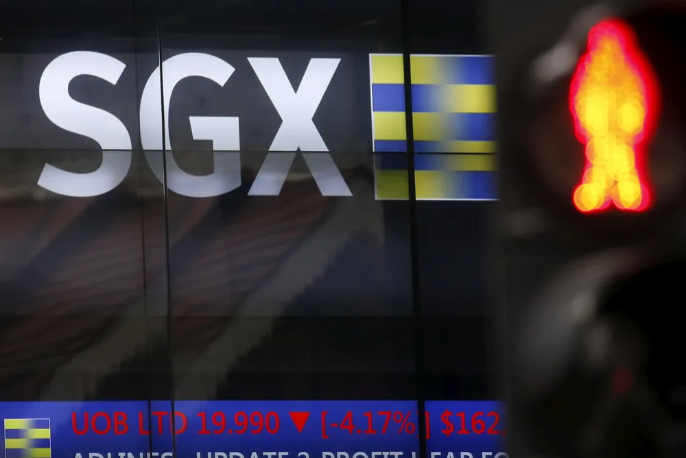 A traffic stop sign is pictured next to the Singapore Exchange stock board.