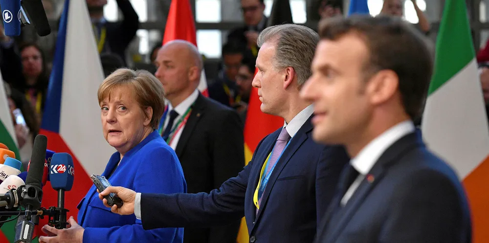 Germany's Chancellor Angela Merkel looks back at French President Emmanuel Macron as they speak to the media ahead of a European Council meeting.