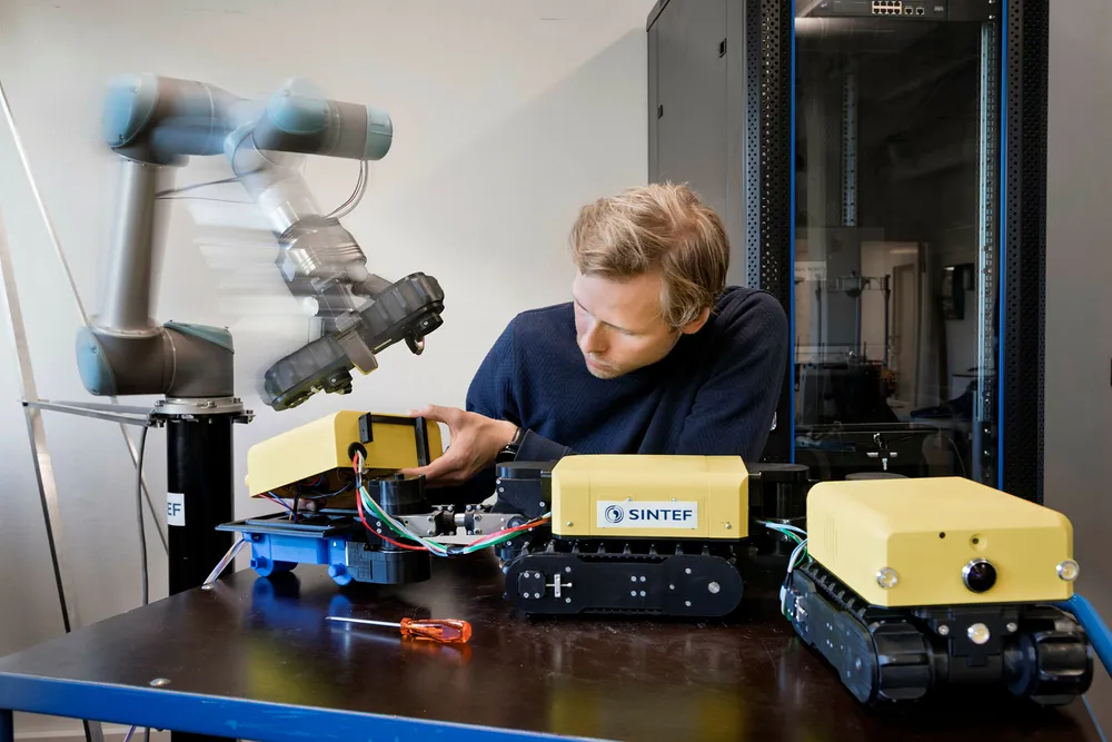 Sintef har utviklet teknologi som får roboter til å unngå kollisjon med andre gjenstander og mennesker – ikke ved å stoppe, men ved å gå rundt hinderet. Her viser forsker Øystein Hov Holhjem hvordan slik teknologi åpner for effektivt samspill mellom roboter og mennesker. Foto: Thor Nielsen