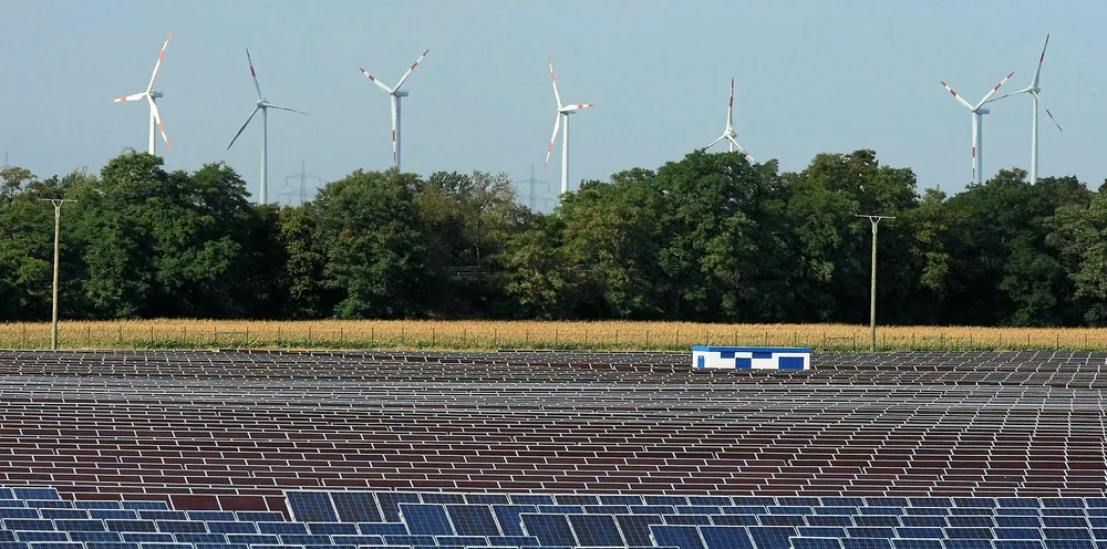 Wind turbines turn behind a PV array in Bitterfeld, Germany.