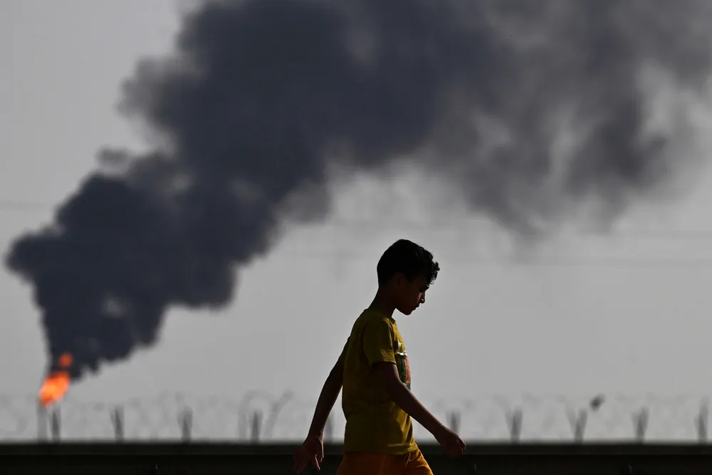 A boy walks near a flare stack in the Rumaylah oilfield near Iraq's southern port city of Basra.