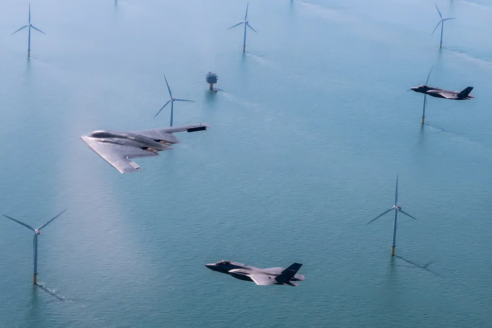 A US Air Force stealth bomber flies above a UK wind farm with two RAF F-35 jets. Stealth technology similar to that used in aircraft could soon be used to reduce the clutter that wind turbines cause military radar systems.