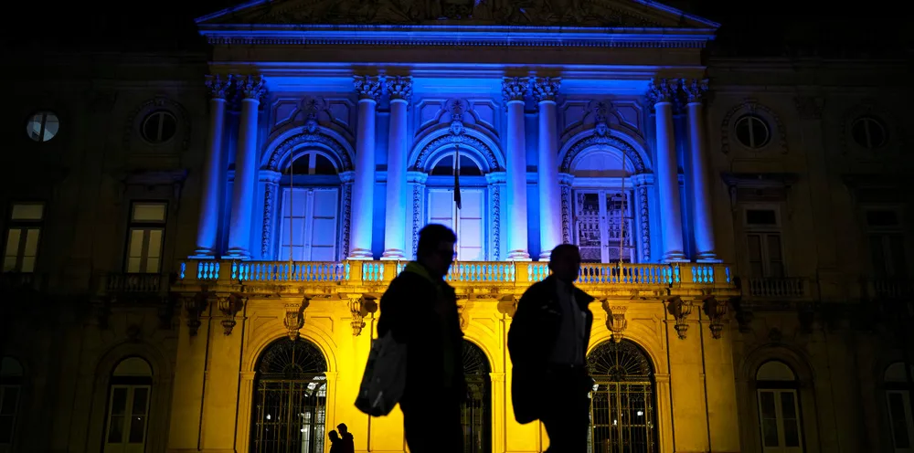 People walk in front of Lisbon’s City Hall lit with the colours of the Ukrainian flag on Monday.
