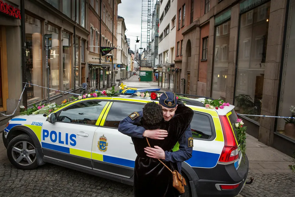 Drottninggatan i Stockholm er Sveriges travleste handlegate der fire mennesker døde fredag. Her får en politimann blomster og en klem av en forbipasserende. Foto: Linus Sundahl-Djerf