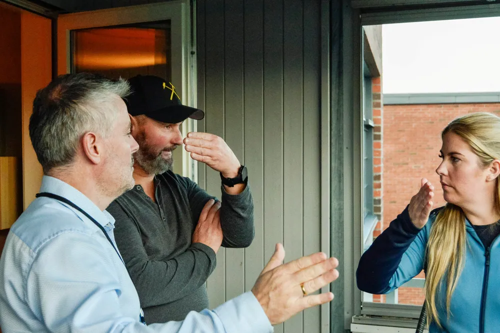 Eiendomsmegler Marius Husby (til venstre) og visningsdeltagerne Ketil Kjeldsberg og Kine Marie Lind med hver sine antagelser om solforholdene på en balkong øst i Trondheim.