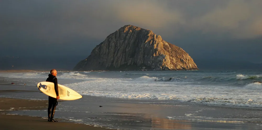 A surfer looks out at the Pacific Ocean near Morro Bay