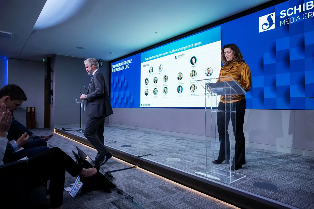 Konsernsjef Kristin Skogen Lund klar til å forklare hvordan Schibsted skal vokse videre i Norden, mens styreleder Ole Jacob Sunde er på vei ned fra scenen under selskapets kapitalmarkedsdag i London.