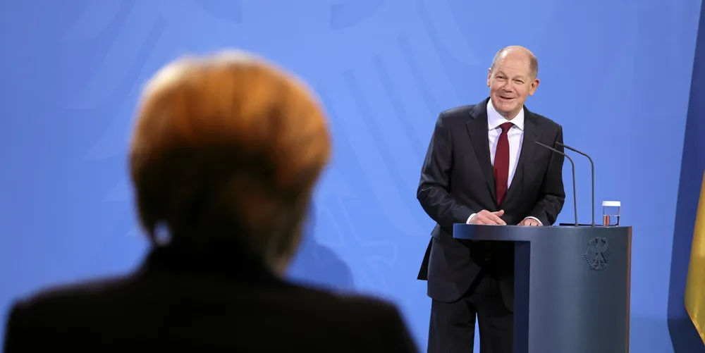 New Chancellor Olaf Scholz speaks during an official transfer of government, with Angela Merkel looking on.