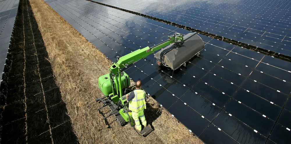A workman uses a machine to clean panels at the 46MW Landmead solar farm near Abingdon, England