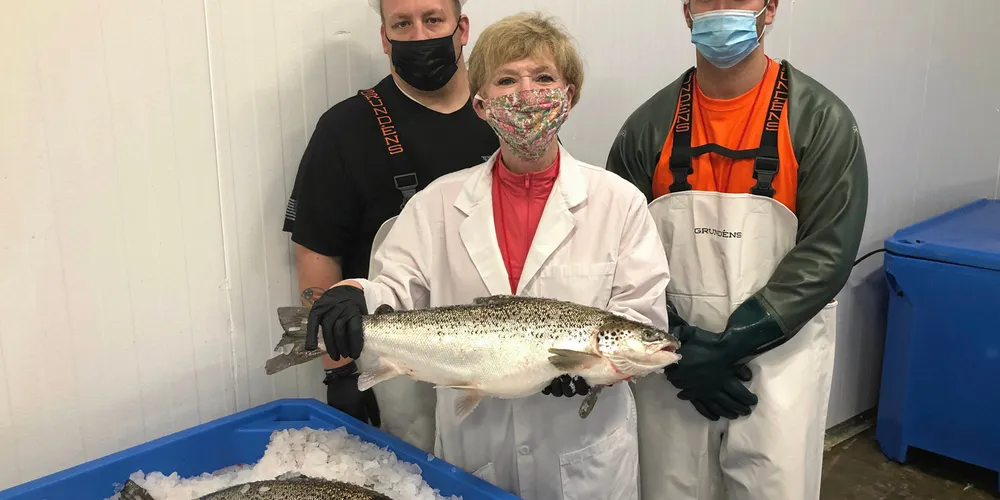 . AquaBounty Processing Associates Skyler Miller (left) and Jacob Clawson (right), with CEO Sylvia Wulf (center) holding the first commercially harvested genetically modified farmed salmon in the US.