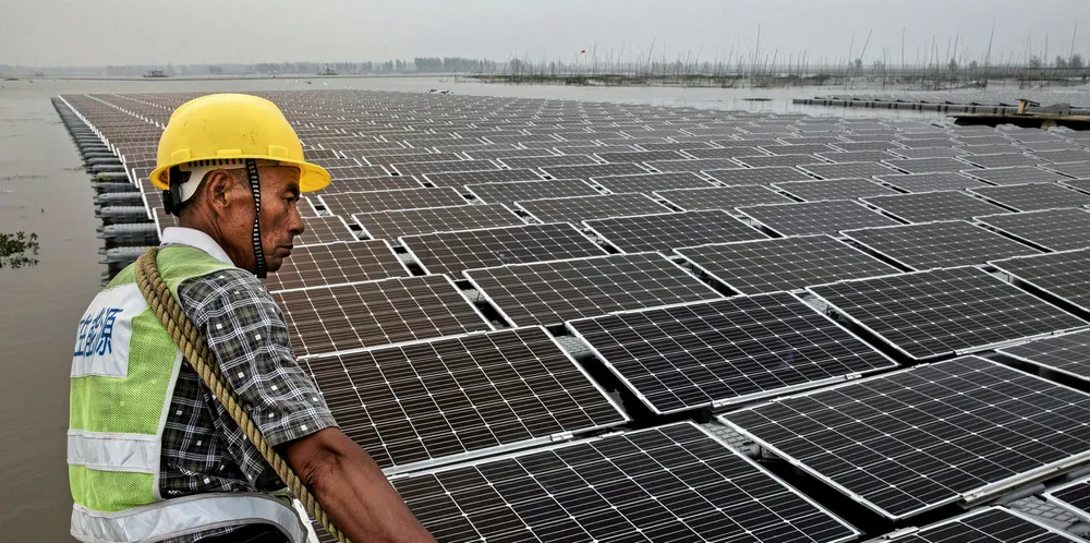 A Chinese worker pulls floating panels that are part of a large floating solar farm project there.