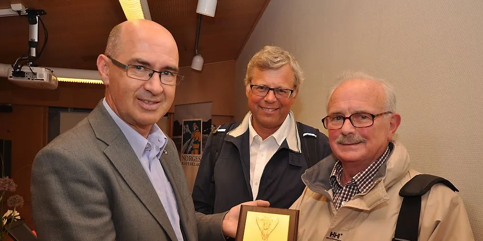 Svein Ove Haugland, assisterende direktør i Norges Råfisklag, gir prisen "Golden Norwegian Prawn Award" til rekekongen Dennis Thomas (t.h.). Foto: Mia Kanstad Kulseng