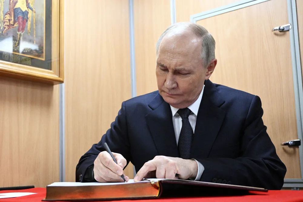 Russian President Vladimir Putin signs a guest book as he visits a nuclear-powered submarine Arkhangelsk, in Murmansk, Russia, in March 2025.