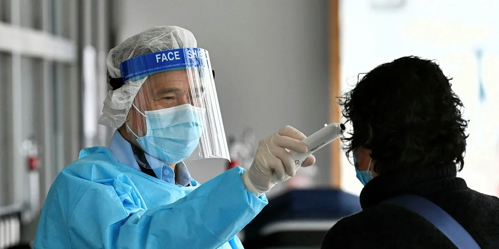 A medical worker wearing protective gear takes the temperature of a woman as she enters Princess Margaret Hospital in Hong Kong.