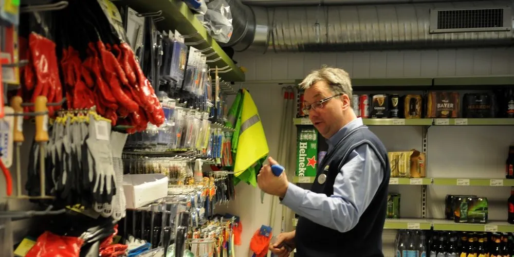 Kjøpmann Børge Larsen sjekker ut noe av utstyret. Bak har ølhylla begynt å tømmes. Det kan se ut til å landliggen setter sitt preg på butikken. Foto: Kjersti Kvile