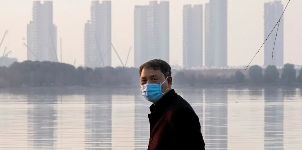 man wears a face mask as he stands along the waterfront in Wuhan in central China's Hubei Province, the epicentre of the Cornavirus outbreak