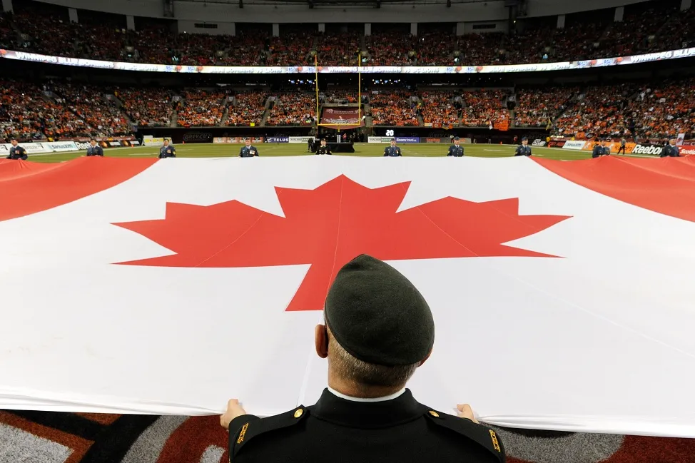 Members of Canada's Armed Forces hold the flag during the singing of the National Anthem before the start of the CFL's 99th Grey Cup football game between the Winnipeg Blue Bombers and the BC Lions in Vancouver, British Columbia November 27, 2011. REUTERS/Todd Korol (CANADA - Tags: SPORT FOOTBALL)