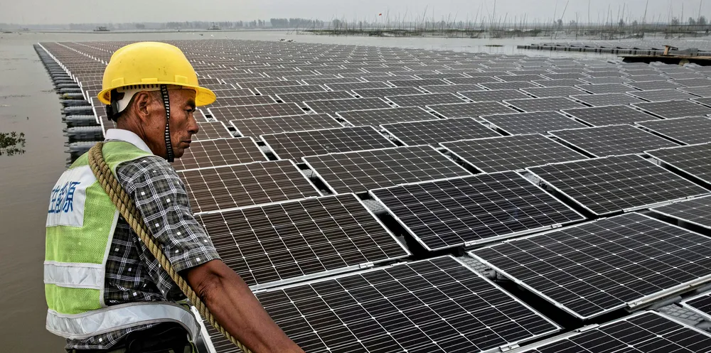 A Chinese worker pulls floating panels that are part of a large floating solar farm project under construction by the Sungrow Power Supply Company on a lake caused by a collapsed and flooded coal mine on June 12, 2017 in Huainan, Anhui province.