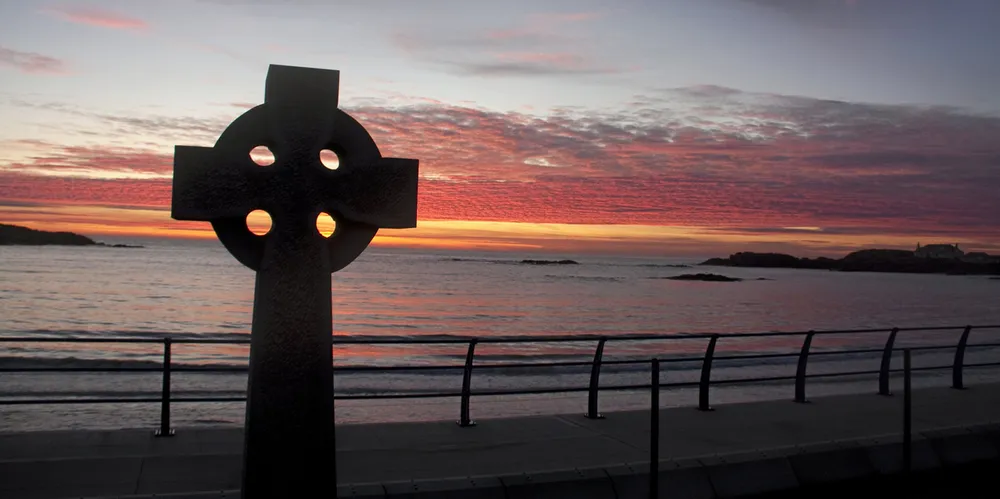 Celtic cross at sunset looking out to the sea from Wales,