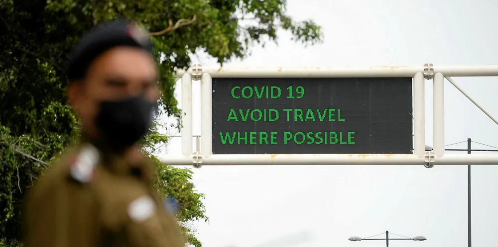 A policeman wearing a facemask stands along a roadsign informing of travel recommendations during a government-imposed nationwide lockdown as a preventive measure against the COVID-19 coronavirus in New Delhi.