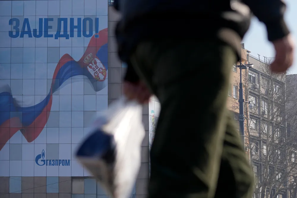 A man walks in front of a billboard showing Russian and Serbian flags, reading: "Together!" and "Gazprom", in the Serbian capital Belgrade in February 2023.