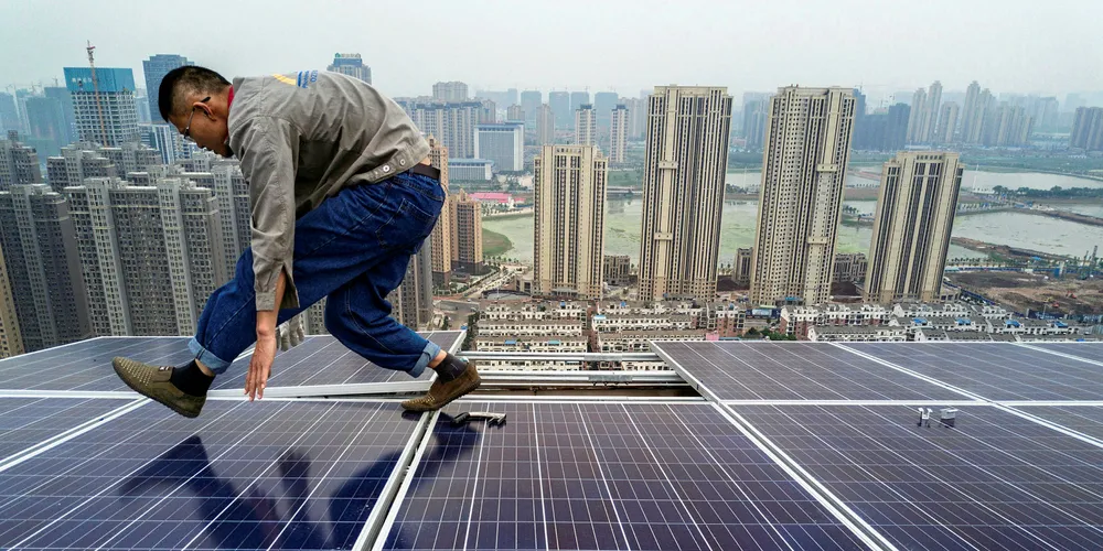 A solar installer keeps his centre of gravity low as he works on a PV project on the roof of a 47-storey building in Wuhan, China. Foto: Getty