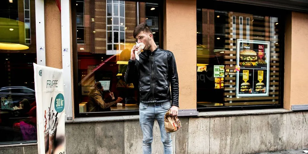 NEI TAKK: De unge spiser mindre og mindre fisk. Usexy og for tungvint. Da er det enklere med en burger. Pintilie Marian (25) har kjøpt en 10-kroners burger på Mc Donalds på Grønland. Foto: Klaudia Lech
