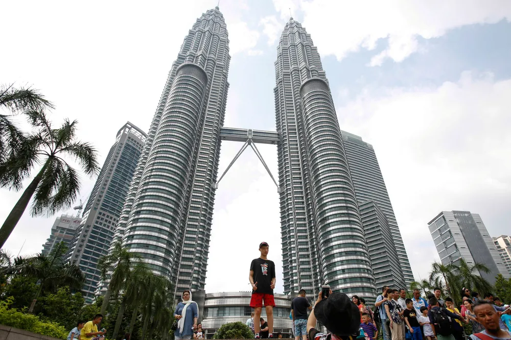 Tourists take souvenir photographs of Malaysian landmark, the Petronas Twin Towers, in Kuala Lumpur.