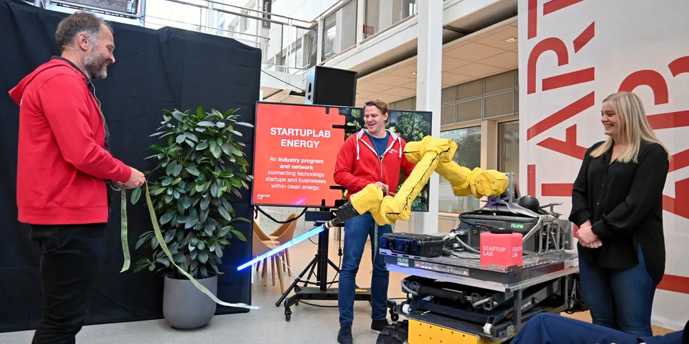 Olje- og energiminister Tina Bru har akkurat trykket på den svarte knappen på den røde terningen. Roboten fra nLink, som er et av selskapene hos Startuplab, klipper over snoren. Startuplab-sjef Per Einar Dybvik (til venstre) og Lars Flesland, som leder Startuplab Energy.
