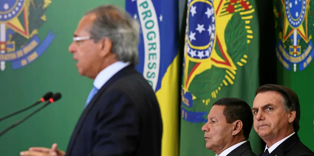 Brazilian President Jair Bolsonaro (R) and Vice-President Hamilton Mourao (C) listen to Finance Minister Paulo Guedes.