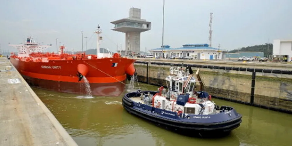 A tug escorts a ship through the Panama Canal.