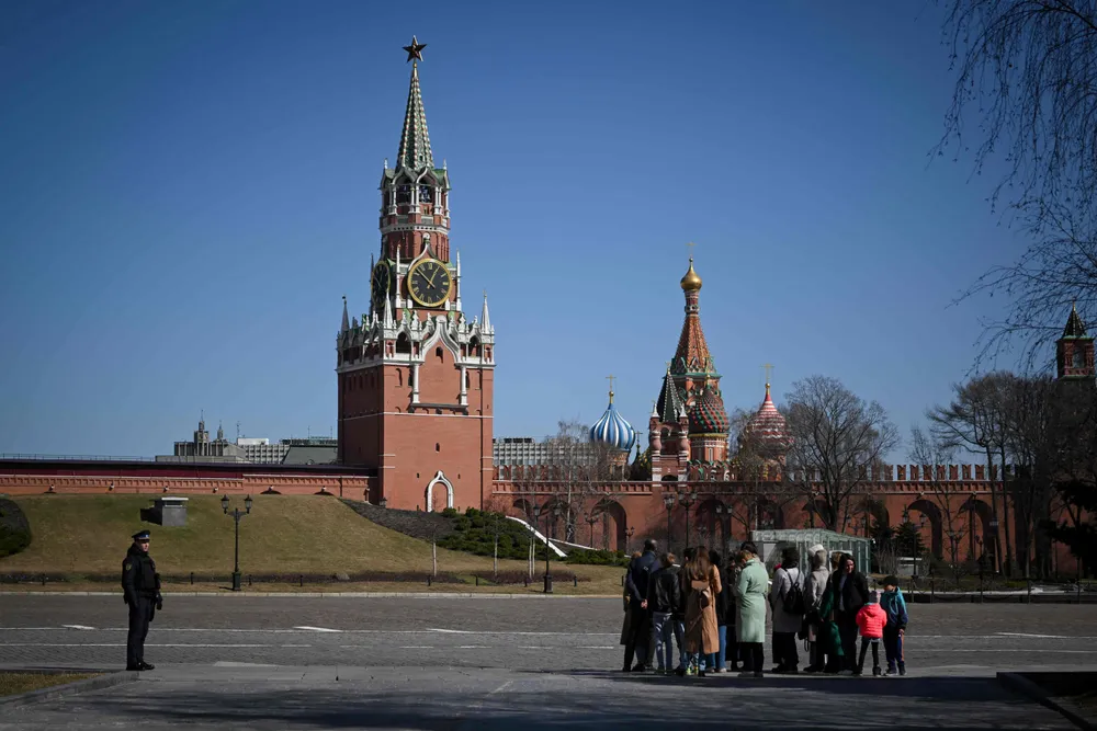 Rouble retreat: a law enforcement officer stands guard as people tour the grounds of the Kremlin.