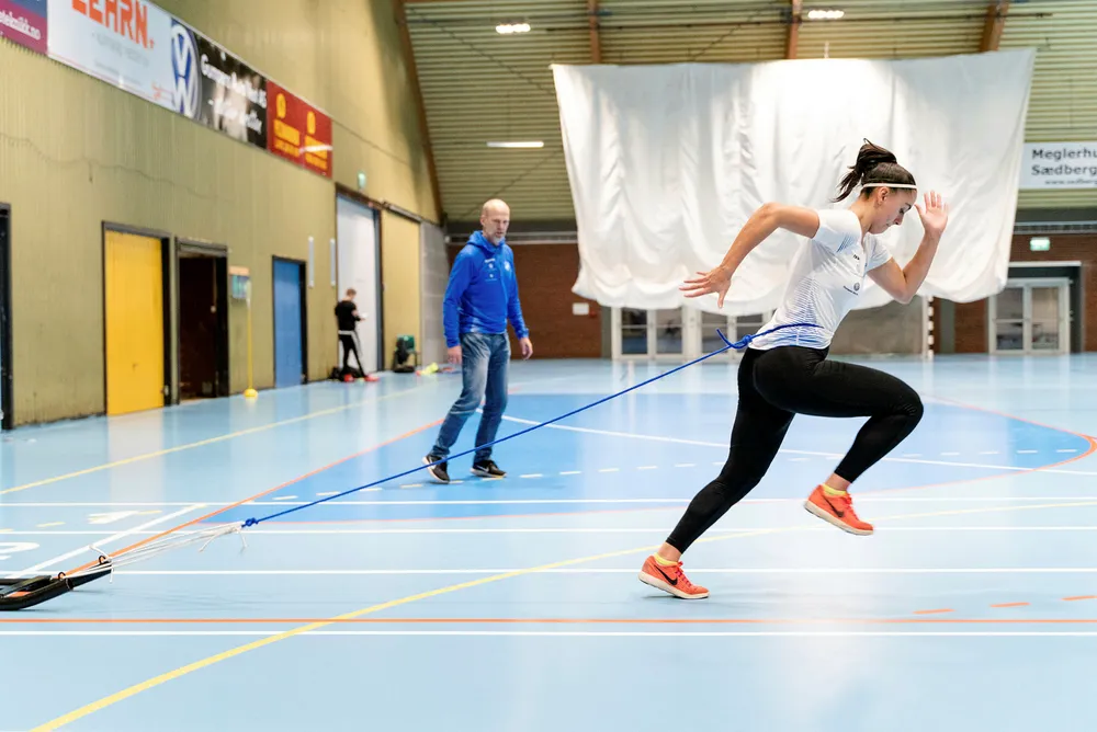 Sprinter Emma Hagen Dihr (19) trener med en ti kilo tung slede på slep for å forbedre teknikken. De fleste løpere kan ha godt av å legge økter med motstand inn i treningsopplegget, mener løpetrener DN har snakket med. Trener Svend Tore Breilid i bakgrunnen.