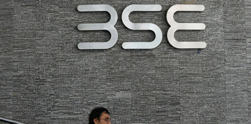 An Indian office goer walks past the Bombay Stock Exchange (BSE) logo at the BSE building in Mumbai.