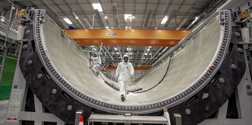 Worker walks down a half-finished Haliade-X 107-metre-long blade